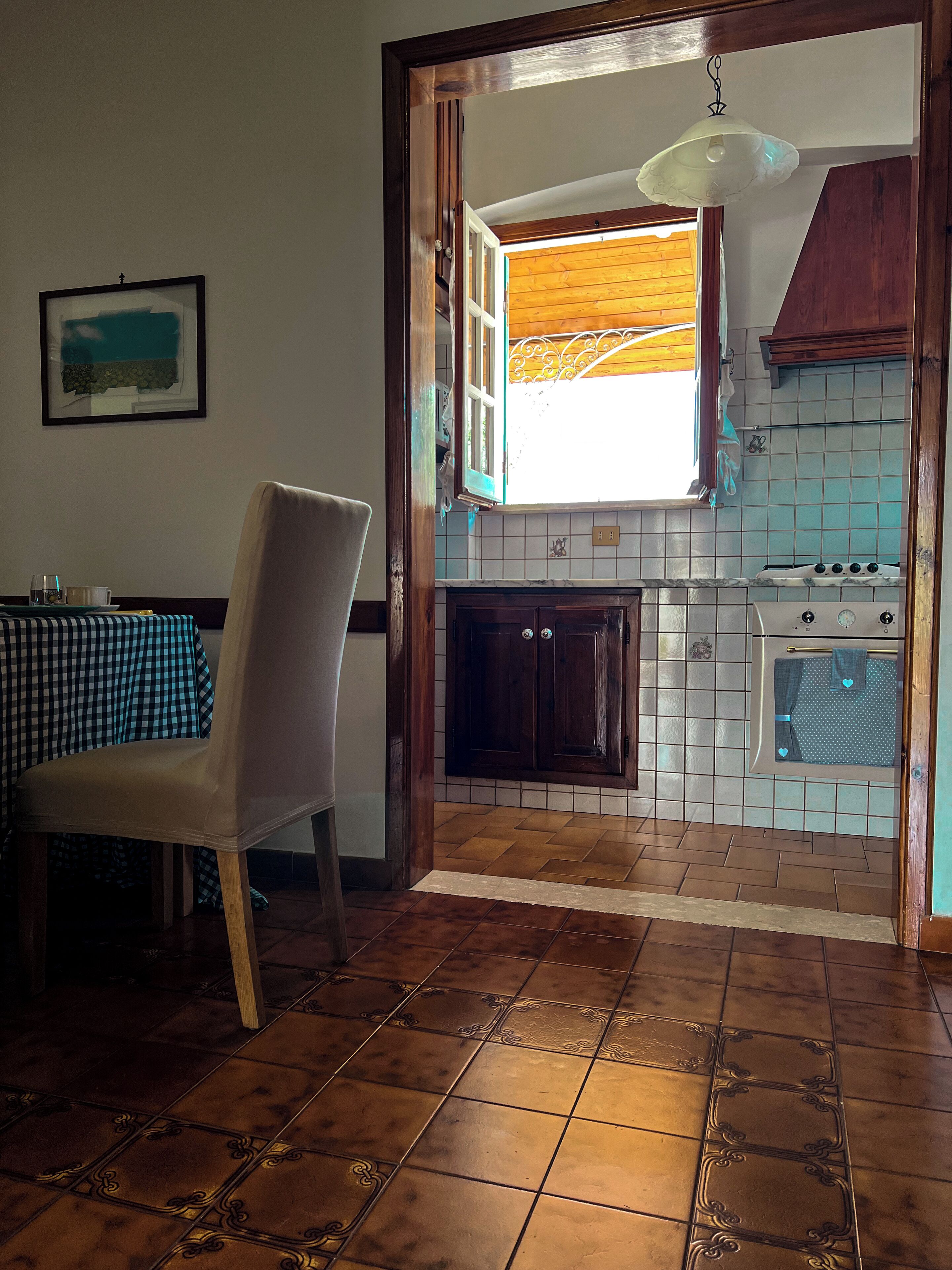 A dining area with a checkered tablecloth, a chair, and a wall-mounted picture.