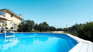 A swimming pool with a white deck, surrounded by a fence and trees. - Bed and Breakfast Nero Buono (Cori)