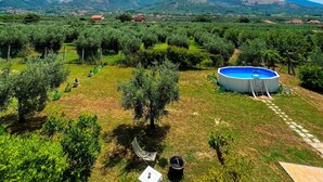 An outdoor area with a swimming pool, a table, and chairs, surrounded by greenery and hills in the background. - Bed and Breakfast Nero Buono (Cori)