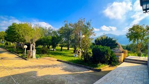 A paved pathway leading to a building with a stone facade, surrounded by greenery and trees. - Bed and Breakfast Nero Buono (Cori)