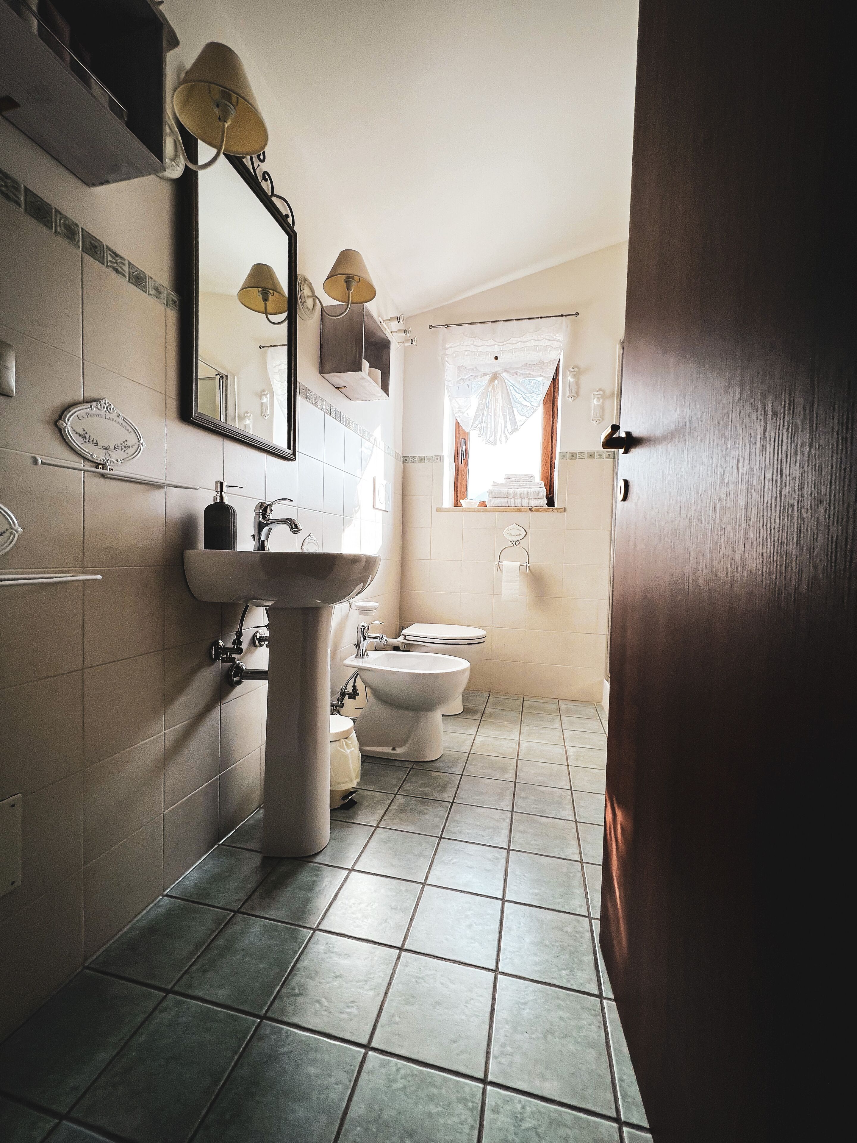 A bathroom with a sink, mirror, and two toilets.