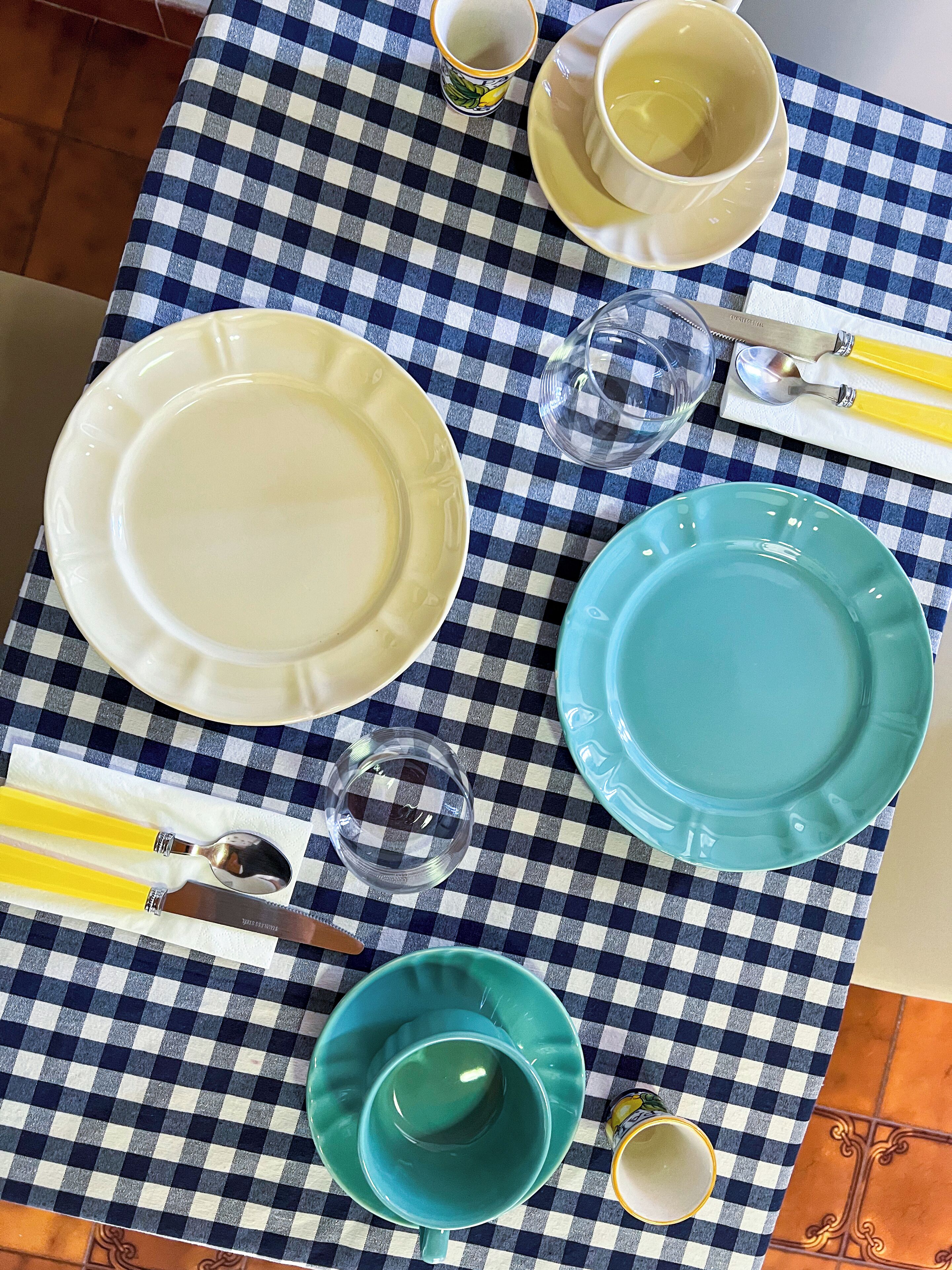 A table set with plates, bowls, and cutlery on a checkered tablecloth.