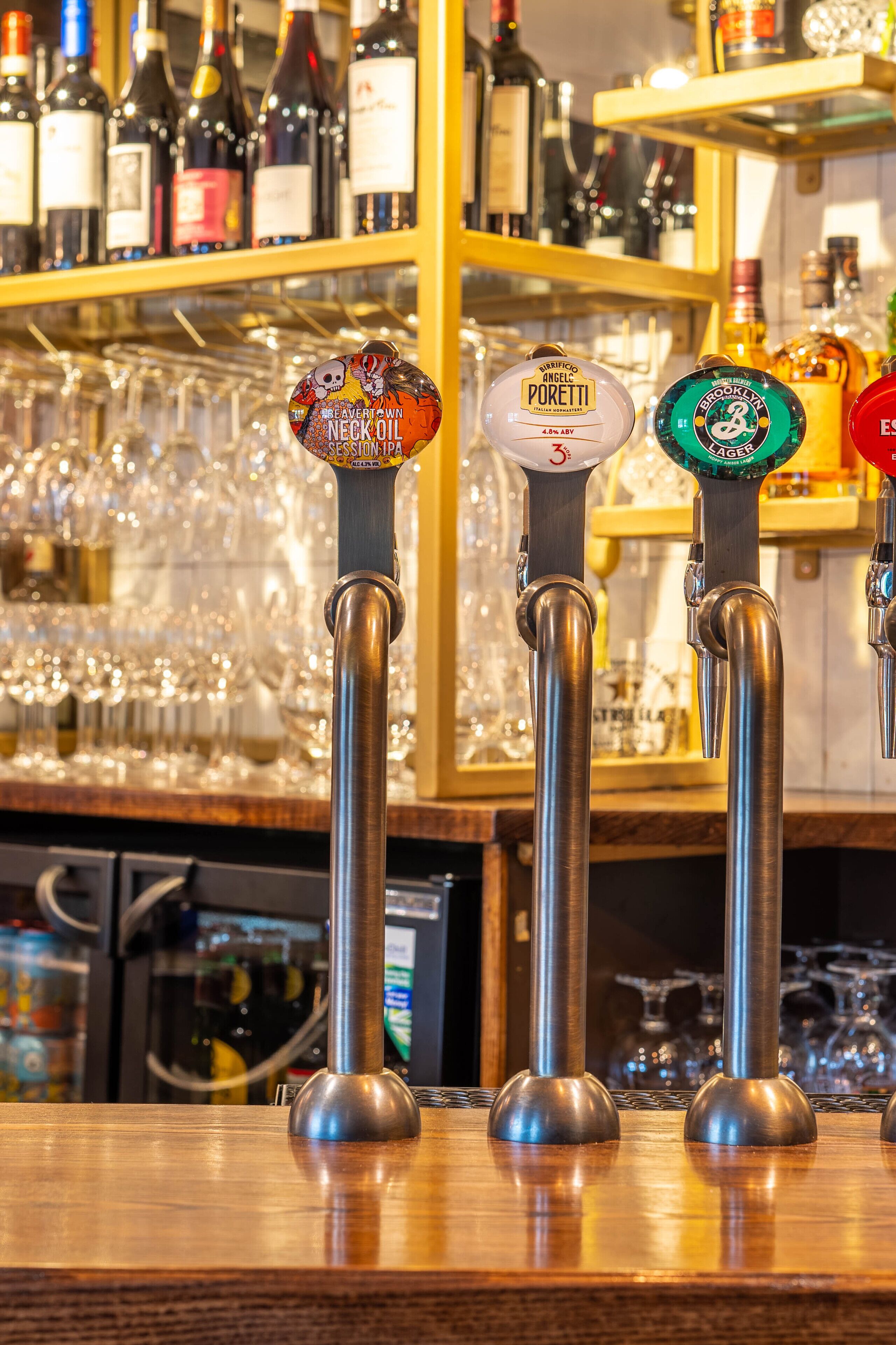 Una barra con tres grifos identificados con diferentes marcas de cerveza.