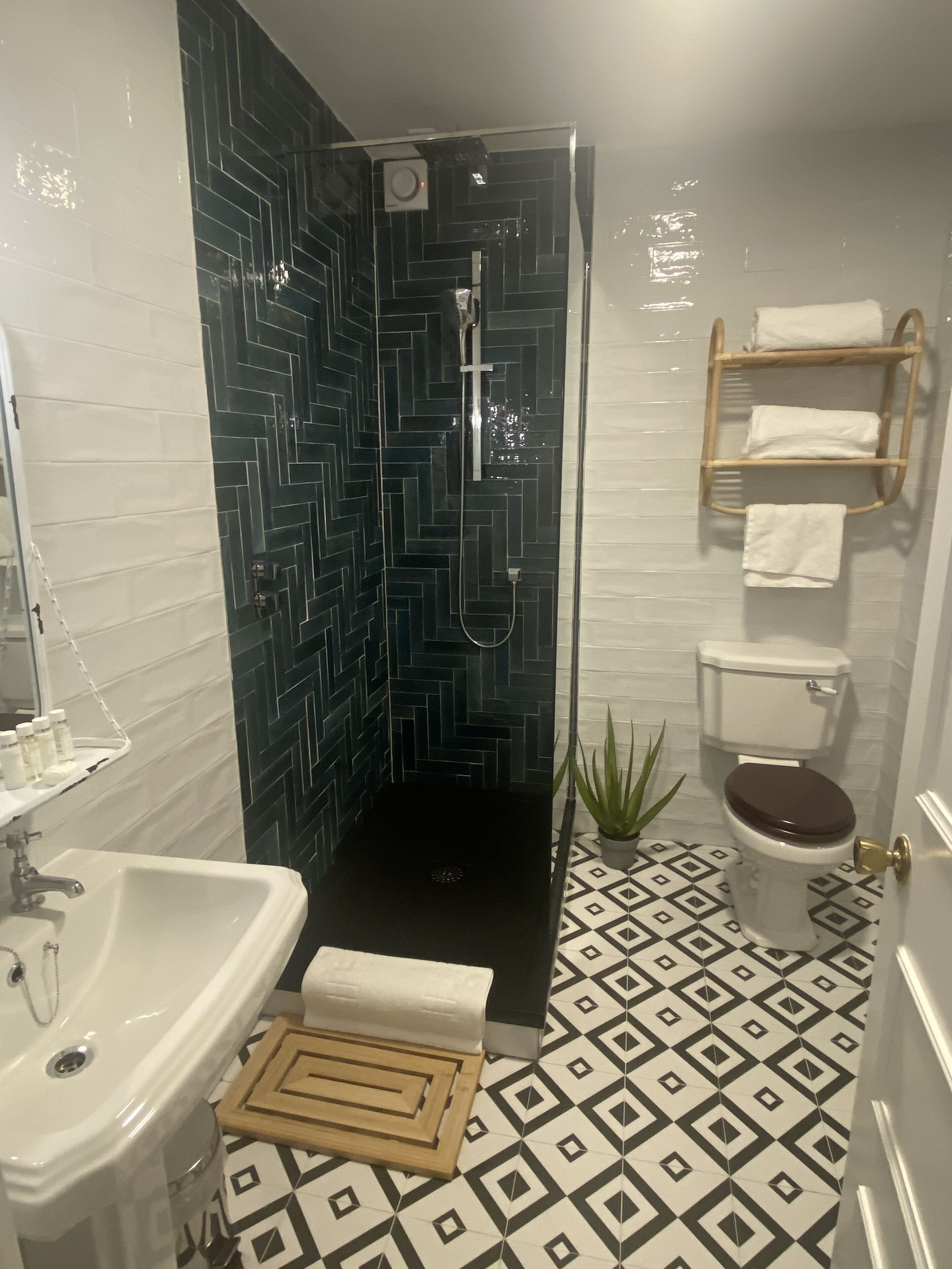 Ein Badezimmer mit Dusche, Waschbecken, Toilette und einem gemusterten Boden.