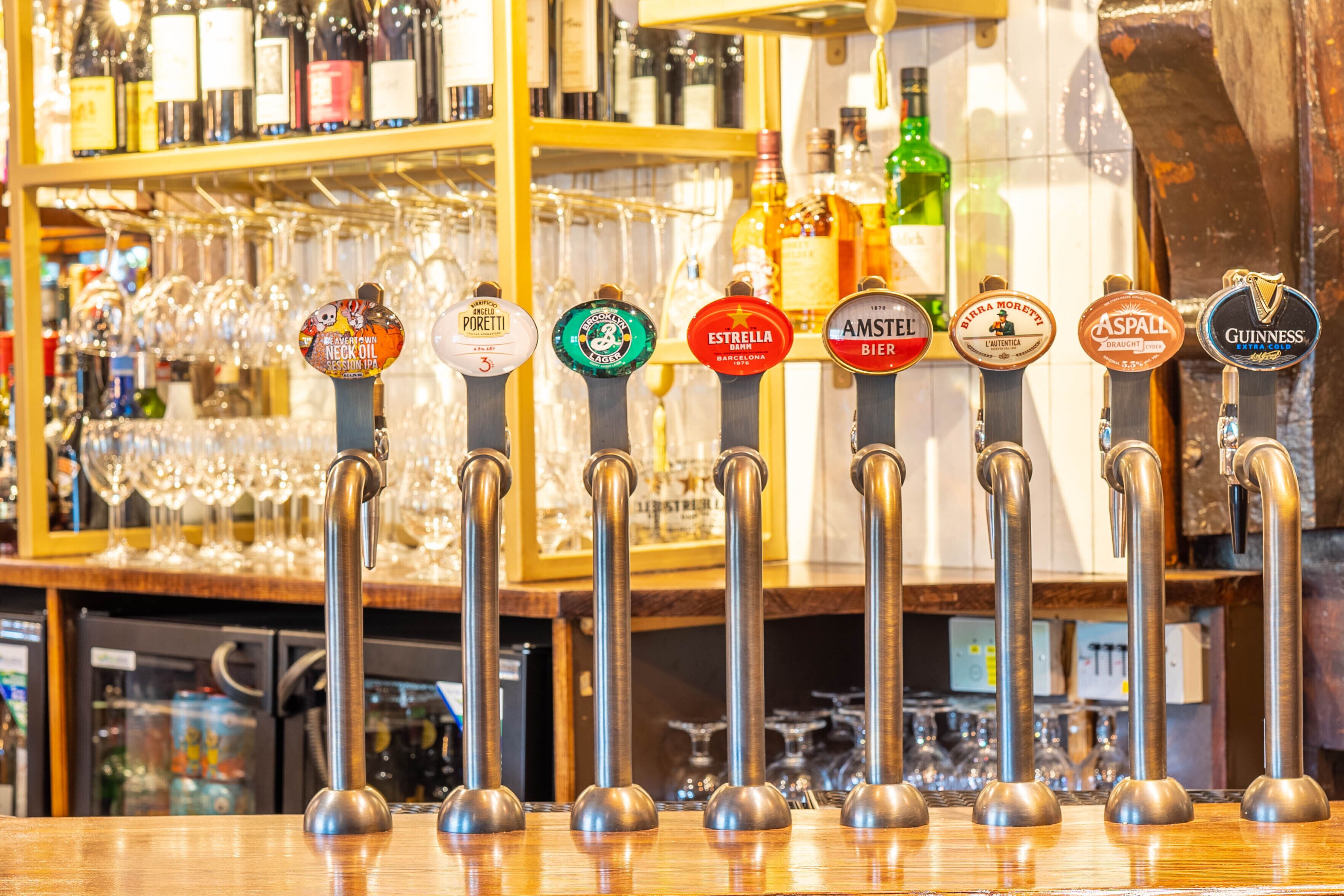 A bar with multiple beer taps and a variety of bottles in the background.