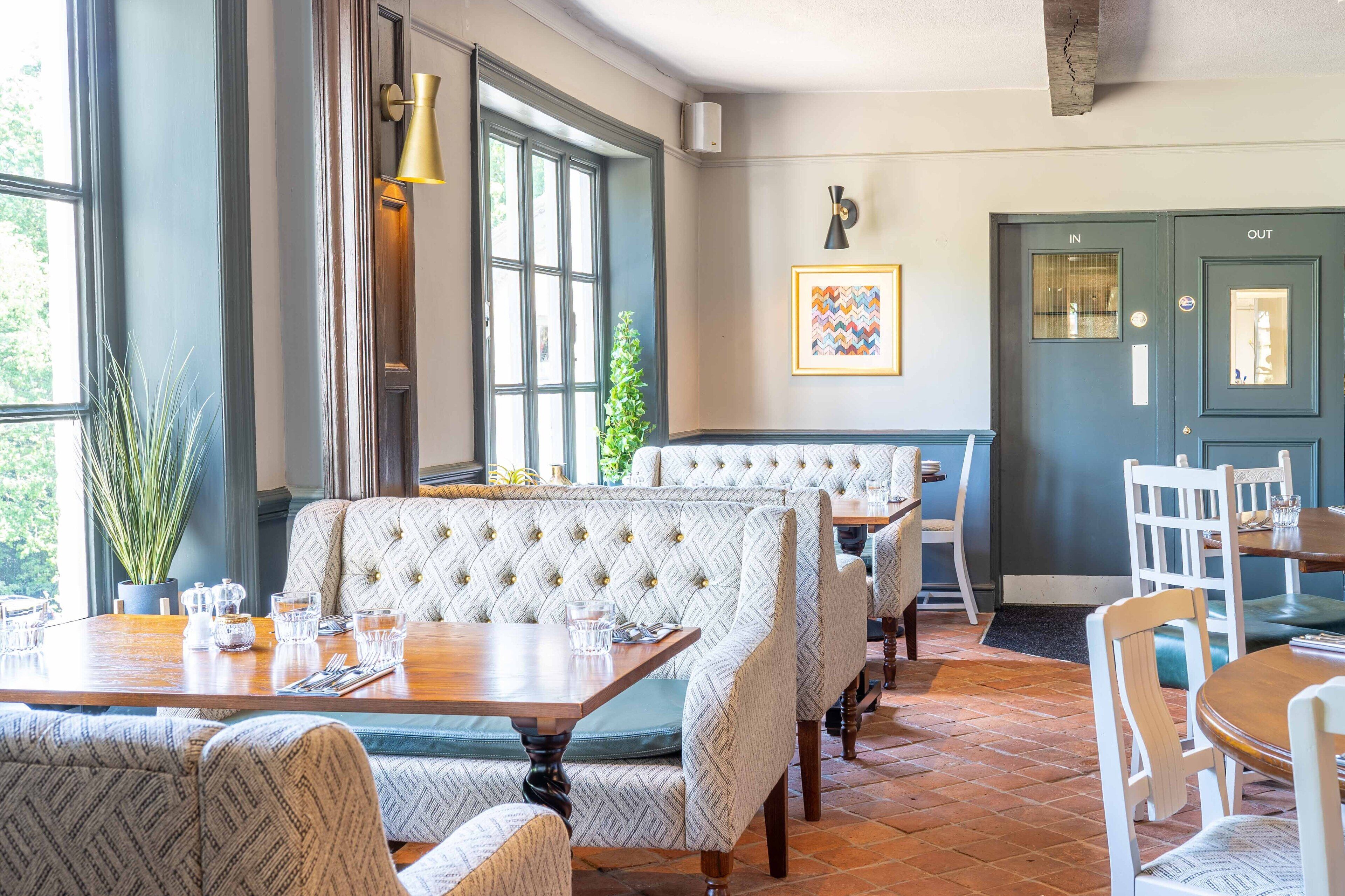 A restaurant with high-backed upholstered booths, wooden tables, and a tiled floor.