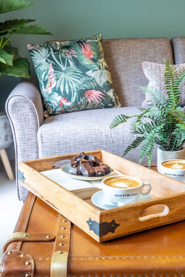 Una bandeja de madera con un plato de brownies y dos tazas de café sobre un sofá de cuero.