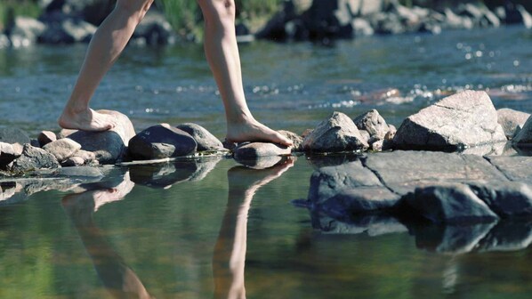 A person standing on rocks in a clear stream.
