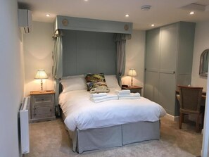 A bedroom with a large bed, two bedside tables with lamps, a chair, and a wardrobe.