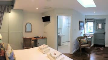 Une chambre d’hôtel comprenant un lit, un bureau, une chaise, une télévision, une salle de bain et une vue sur l’extérieur.