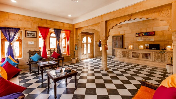 A lobby with checkered flooring, a reception desk, and seating areas with colorful cushions. - Boutique Helsinki (Jaisalmer)