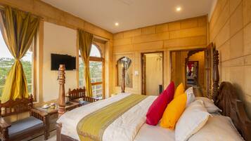 A spacious bedroom with a large bed, wooden headboard, and a television on the wall.