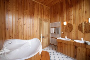 Ein Badezimmer im Chalet-Stil mit Holzausbau, einer freistehenden Badewanne, einem Waschtisch mit zwei Becken und einem Handtuchhalter.