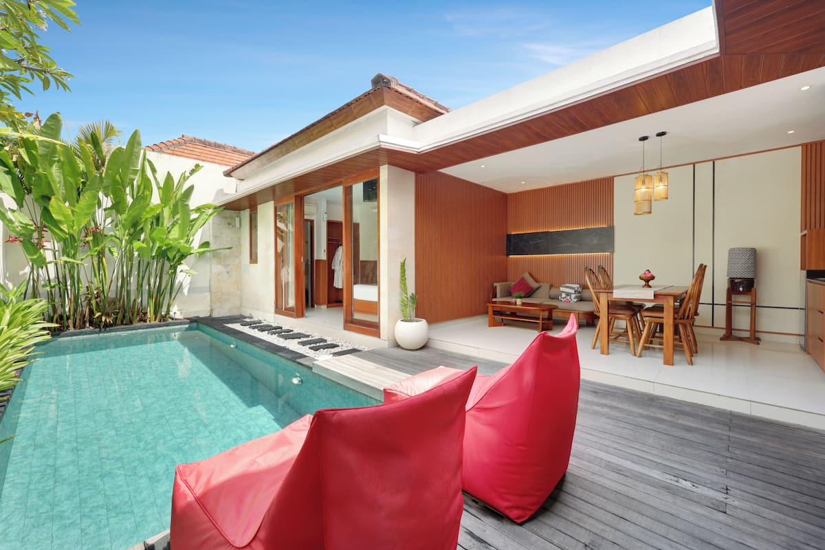 A modern house with a swimming pool, wooden deck, and a dining area with a table and chairs.