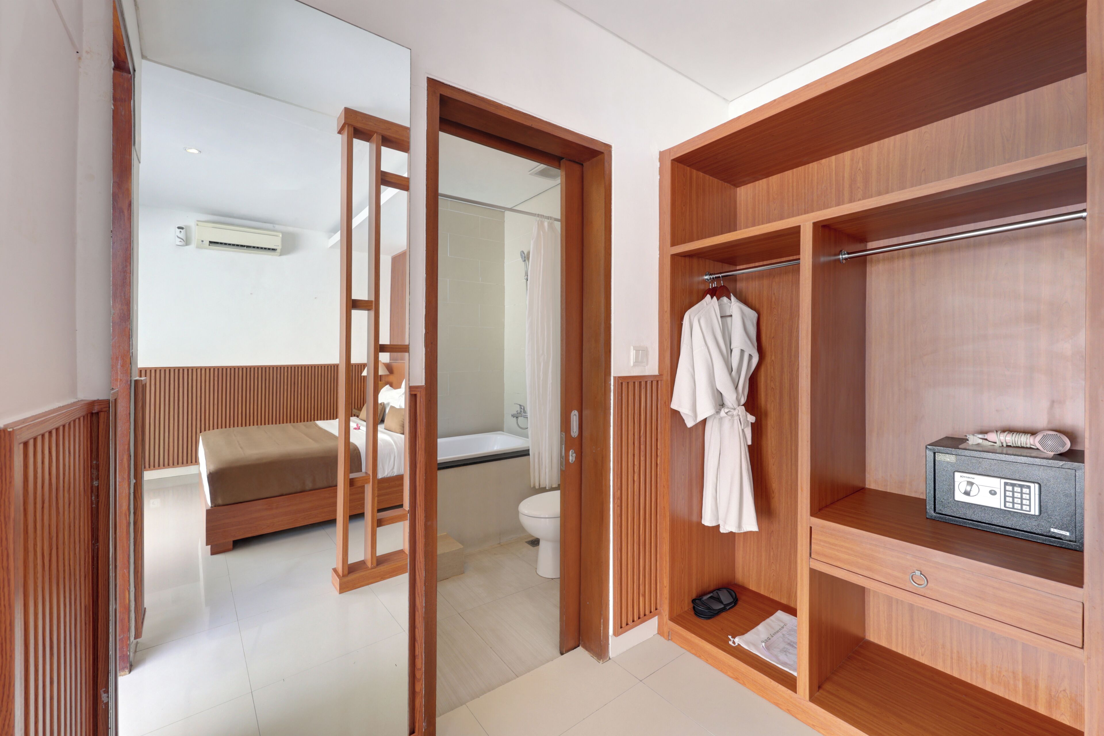 Una camera d'albergo con un armadio in legno, un letto, un bagno con doccia e una cassaforte.