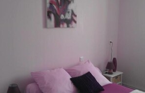 Un dormitorio con cama, mesita de noche y lámpara de pared.