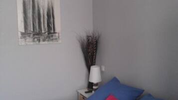 A bedroom with a bed, a nightstand, a lamp, and a wall-mounted painting.