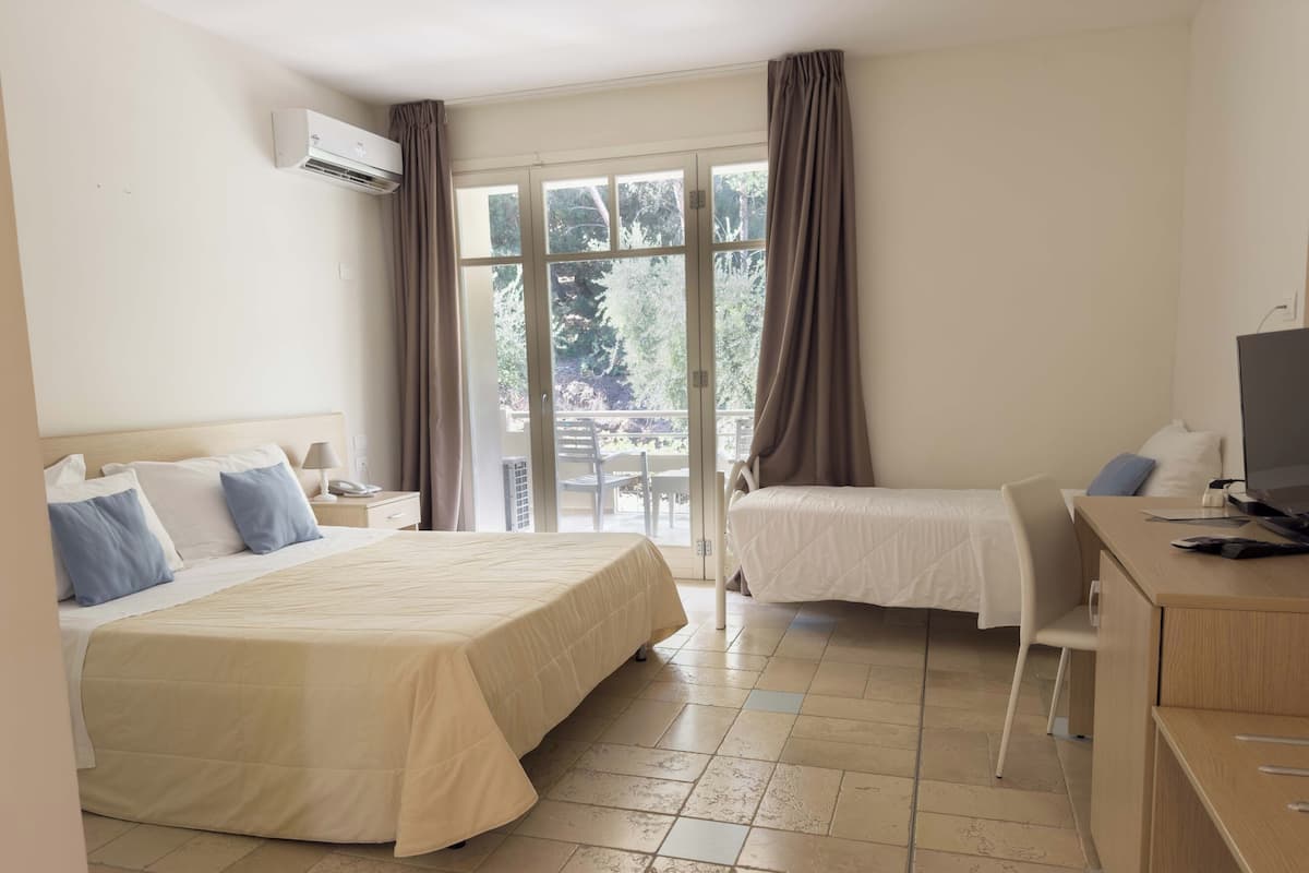 A hotel room with a bed, a desk, a chair, a television, and a window with curtains.