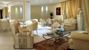 A spacious living room with a high ceiling, elegant furniture, and a large window with curtains. - Hotel Baia Dei Faraglioni (Mattinata)