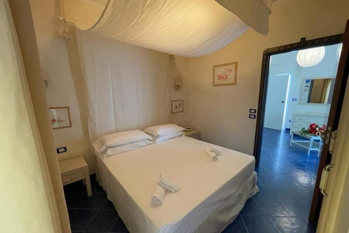 A bedroom with a large bed, a nightstand, and a door leading to a bathroom.