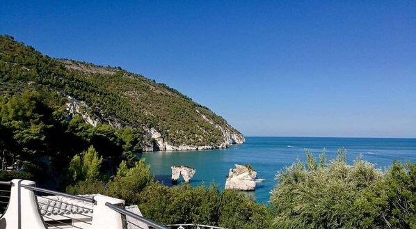 A coastal landscape with rocky outcrops and a clear blue sea.