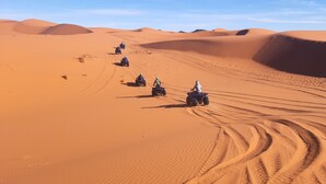 A desert landscape with sand dunes and four off-road vehicles. - Camp Under Stars - Adults Only (Taouz)