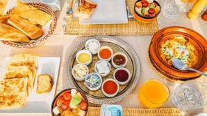 A breakfast setting with bread, a variety of dips, a bowl of fruit, and a bowl of scrambled eggs. - Camp Under Stars - Adults Only (Taouz)