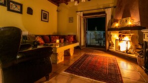 A cozy living room with a fireplace, a sofa, and a coffee table. - Ifigenia Theriso Village (Chania)
