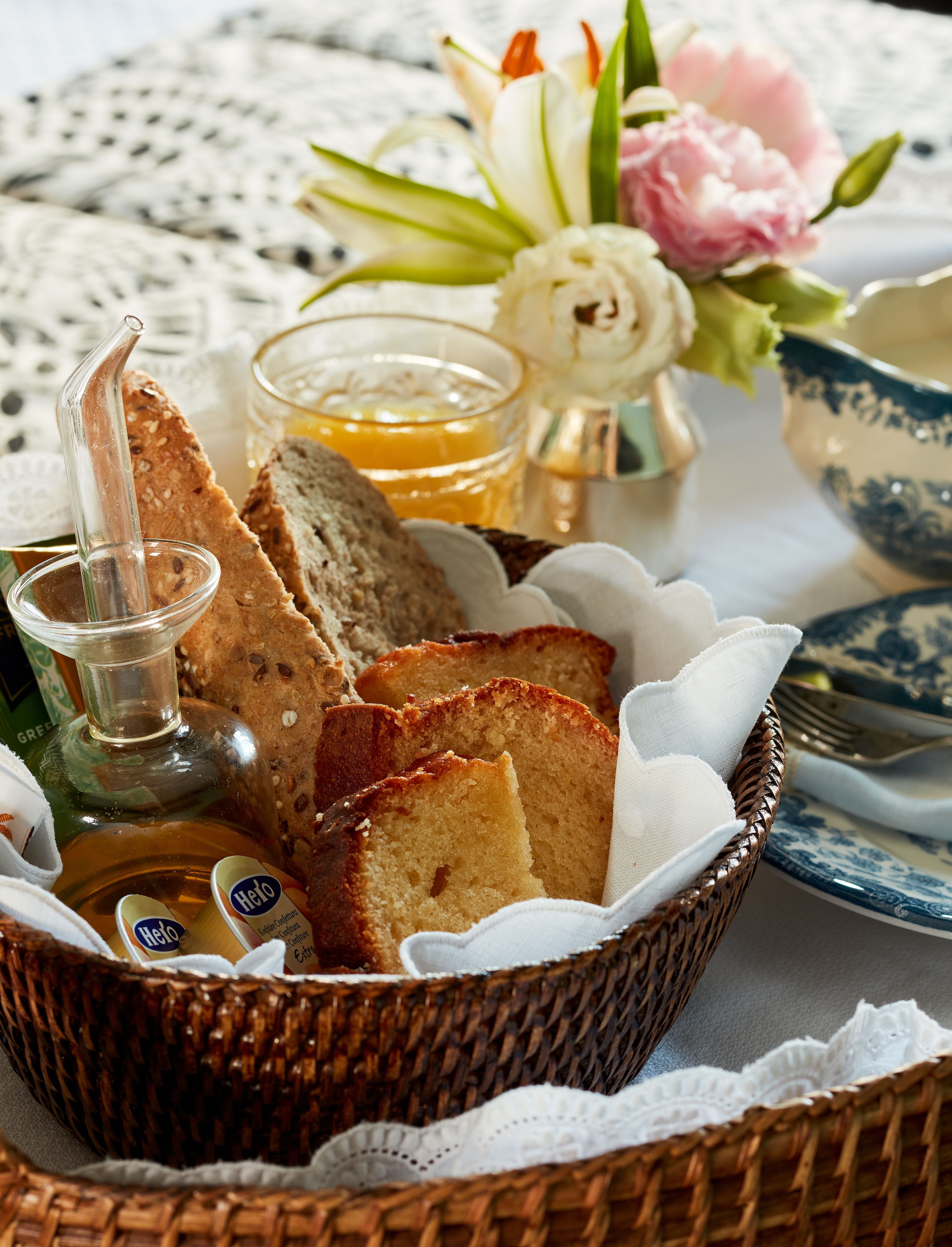 Een rieten mand gevuld met sneetjes brood, een honinglepel en een glas honing.