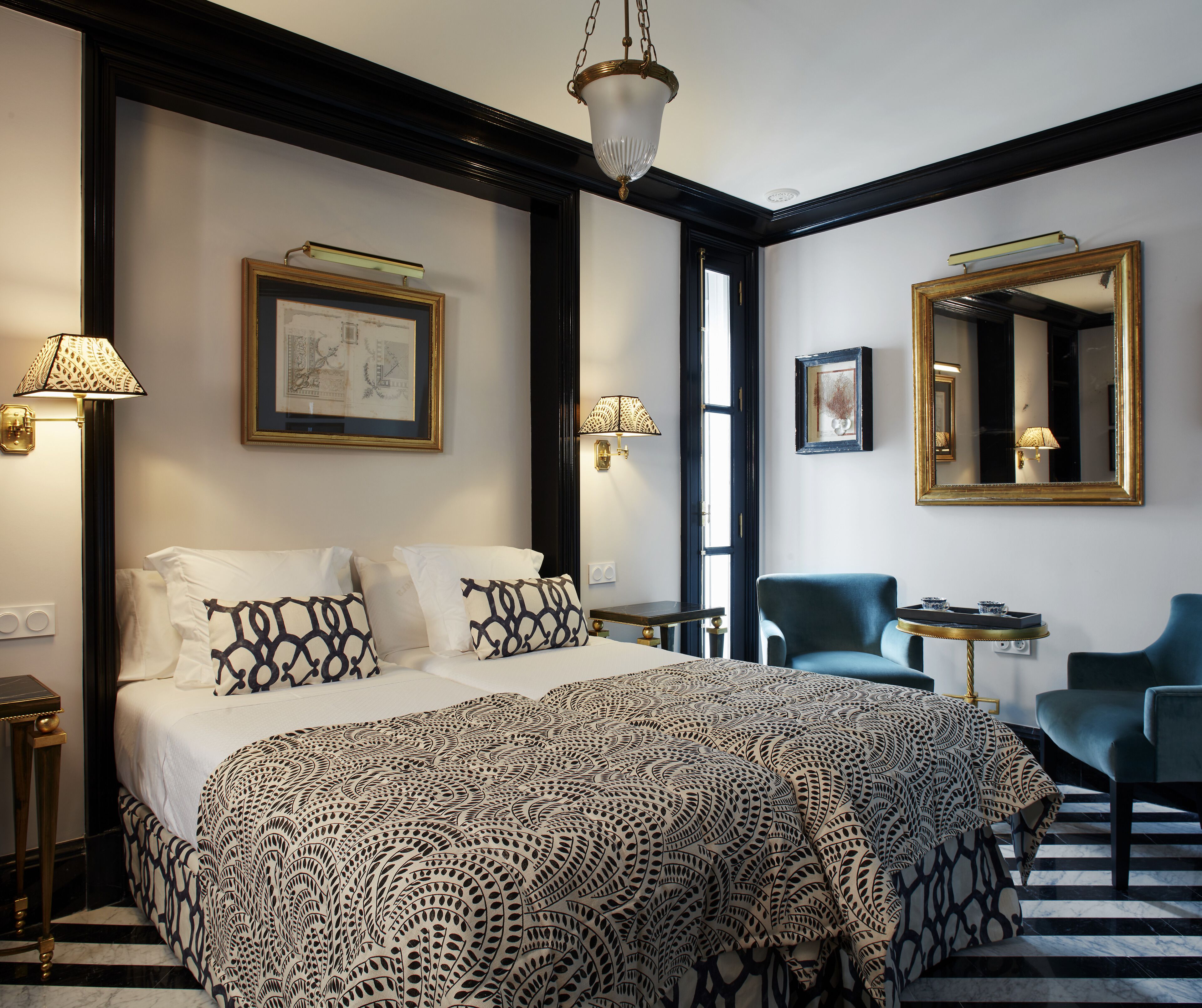 Habitación de hotel con una cama grande, dos sillas, un escritorio y un espejo.