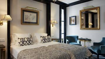 Habitación de hotel con una cama grande, dos sillas, un escritorio y un espejo.
