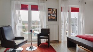 Una moderna camera d'hotel con un letto, due poltrone, un tavolino e un tappeto rosso.