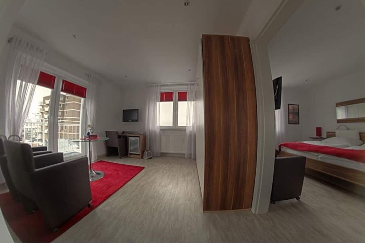A modern hotel room with a large bed, a desk, a chair, and a TV.