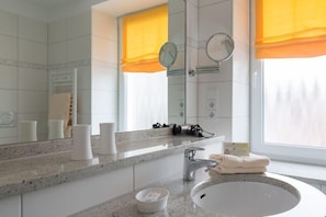 A modern bathroom with a granite countertop, a white sink, and two mirrors. - Hotel Christiansen (Cuxhaven)
