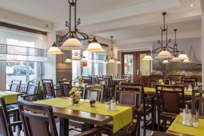 A restaurant with multiple tables, each covered with a yellow tablecloth and set with salt and pepper shakers. - Hotel Christiansen (Cuxhaven)