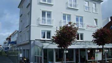 Ein mehrstöckiges Hotel mit moderner Fassade, Balkonen und einem Restaurant sowie Café im Erdgeschoss.