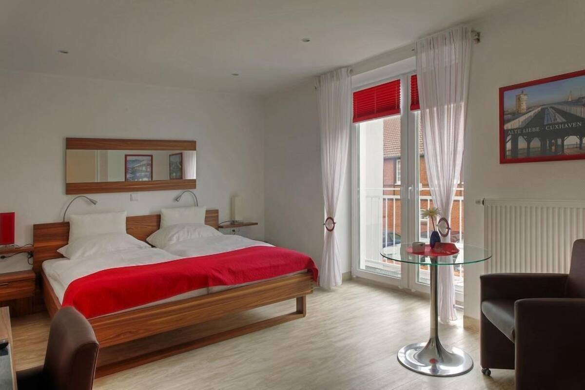 A modern hotel room with a wooden bed, a glass table, and a view of a bridge.