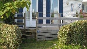 Une maison mobile dotée d’une terrasse et d’une plaque portant le numéro « 26 ».
