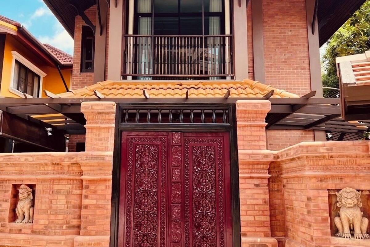 Une maison à deux étages avec un balcon, une porte décorative et une statue de lion.