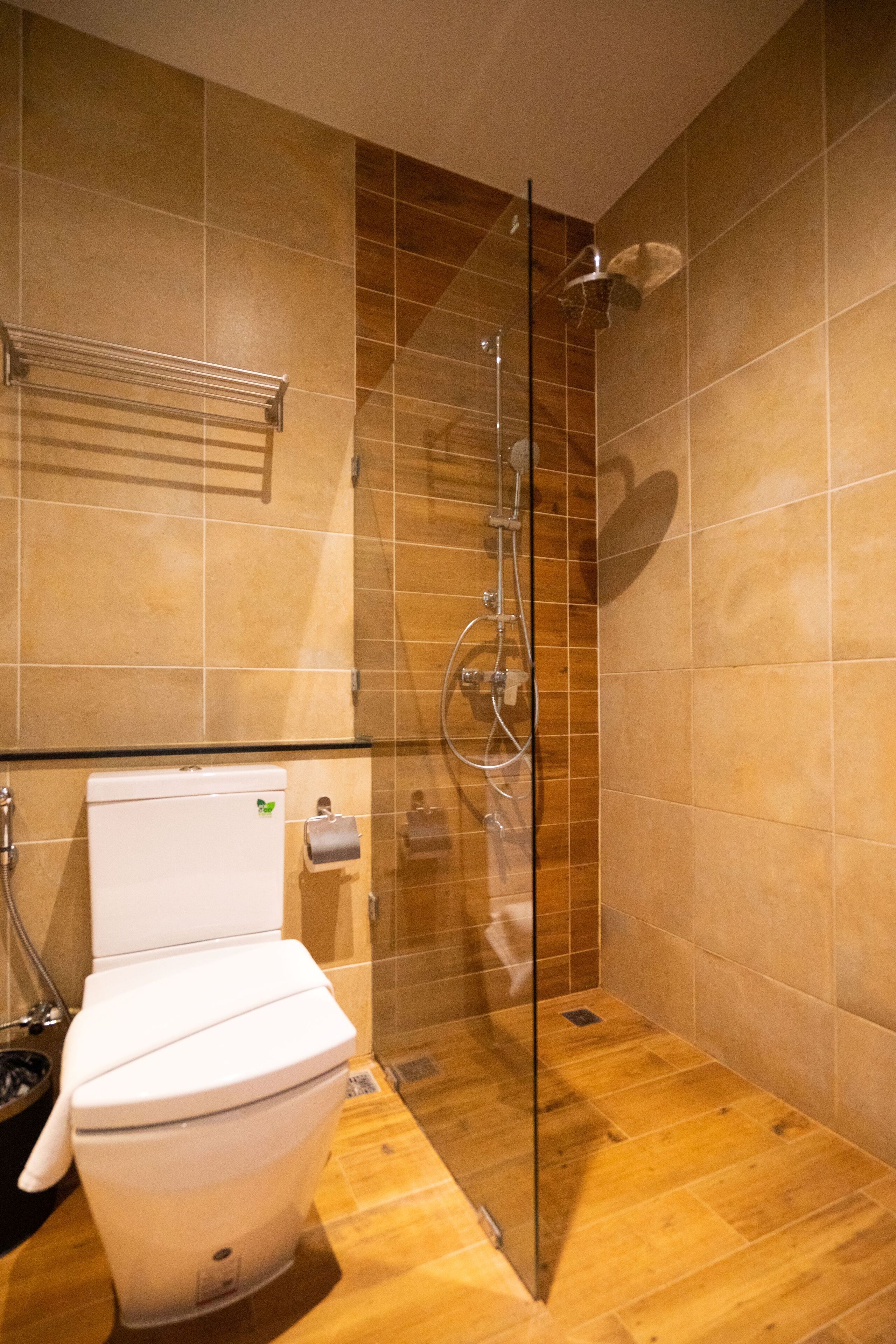 A modern bathroom with a glass shower enclosure, a toilet, and a towel rack.