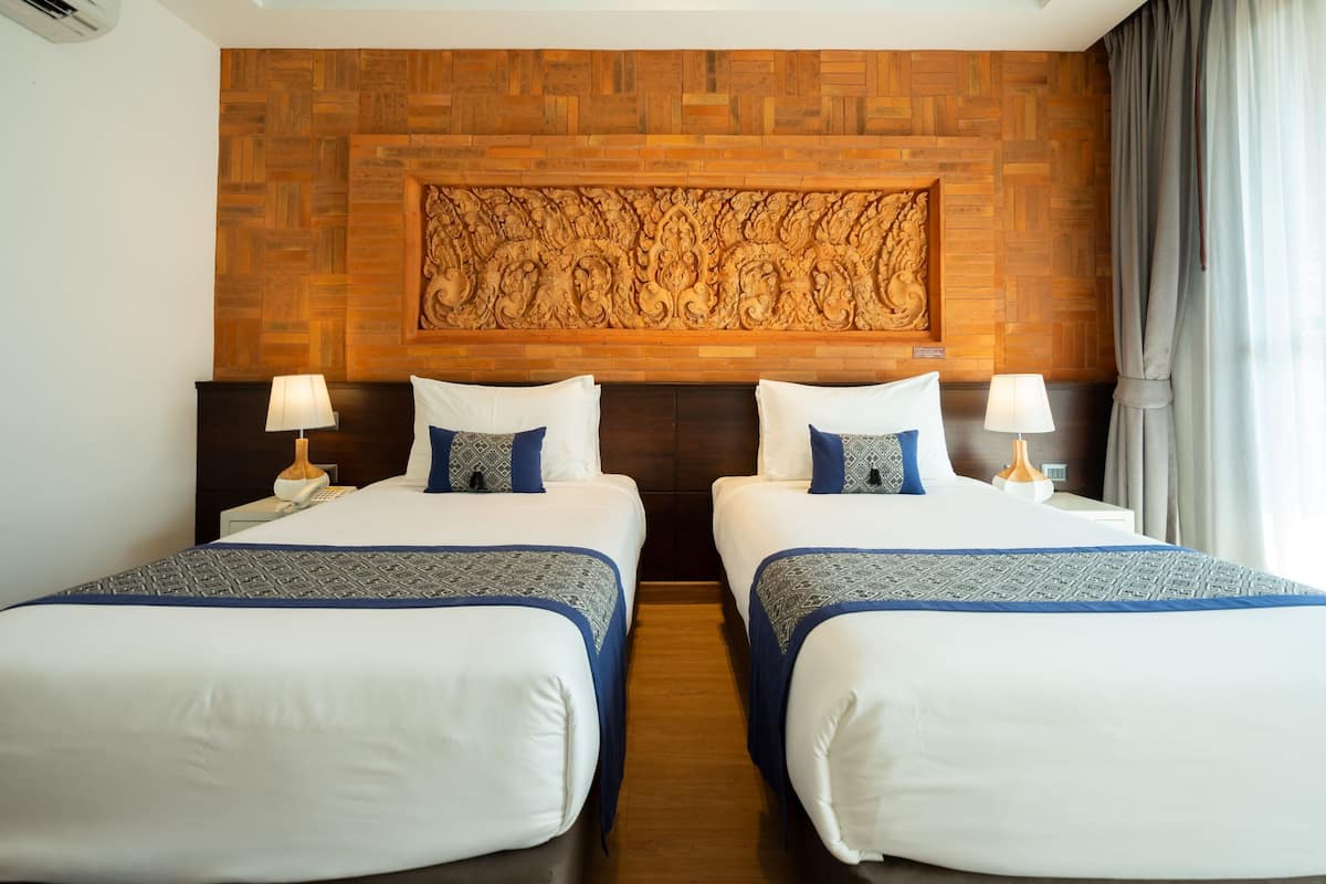 Une chambre d’hôtel avec deux lits, une tête de lit en bois et un élément décoratif mural.
