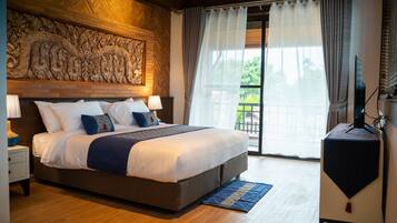 A bedroom with a large bed, a television, and a view of the outdoors.