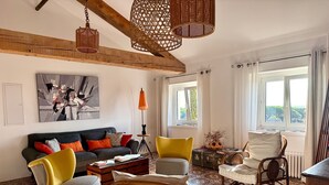 Un salón con sofá, sillas, mesa de centro, lámpara y ventana con cortinas.