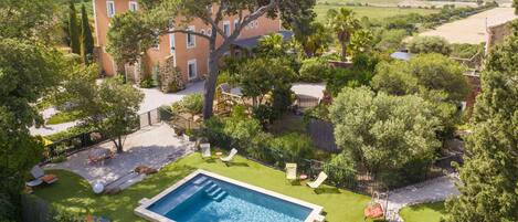 A large rectangular swimming pool surrounded by a well-maintained lawn, with a stone wall and a wooden deck.