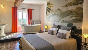 Un dormitorio con una cama grande, una bañera y un mural de un paisaje.