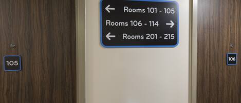 A directional sign indicating room numbers 101-105 to the left, 106-114 to the right, and 201-215 to the left.