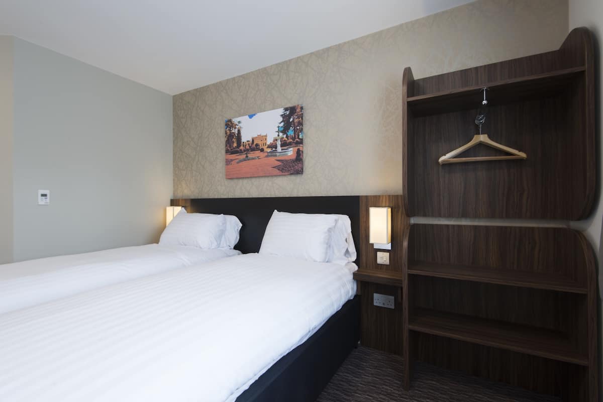 Une chambre d’hôtel avec un grand lit, une armoire en bois, un tableau accroché au mur et des lampes de chevet.
