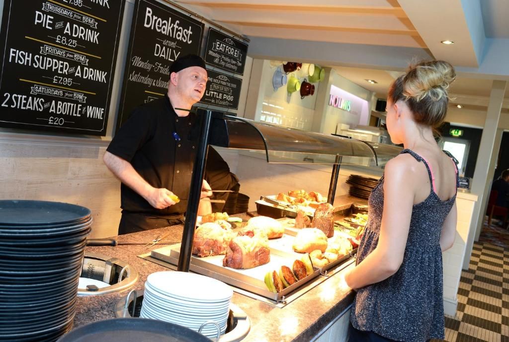 A buffet counter with various food items and a menu board in the background.