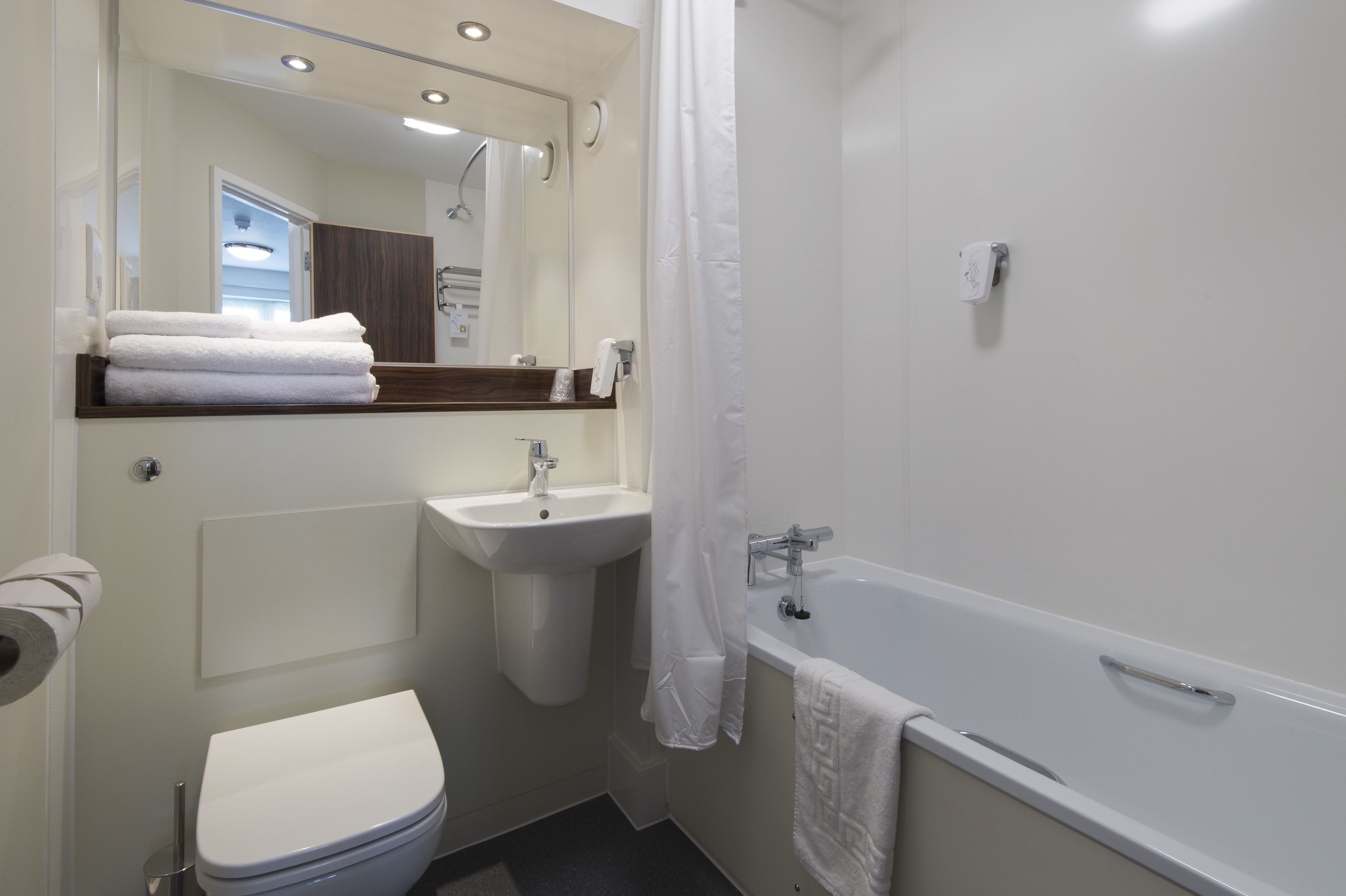 Een moderne badkamer met toilet, wastafel en bad.
