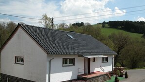 Ein weißes Gebäude mit dunklem Dach, einem Schild mit der Aufschrift 'www.rolling-vista.com Ferien Erlebnis' und einer kleinen Veranda mit Stufen.